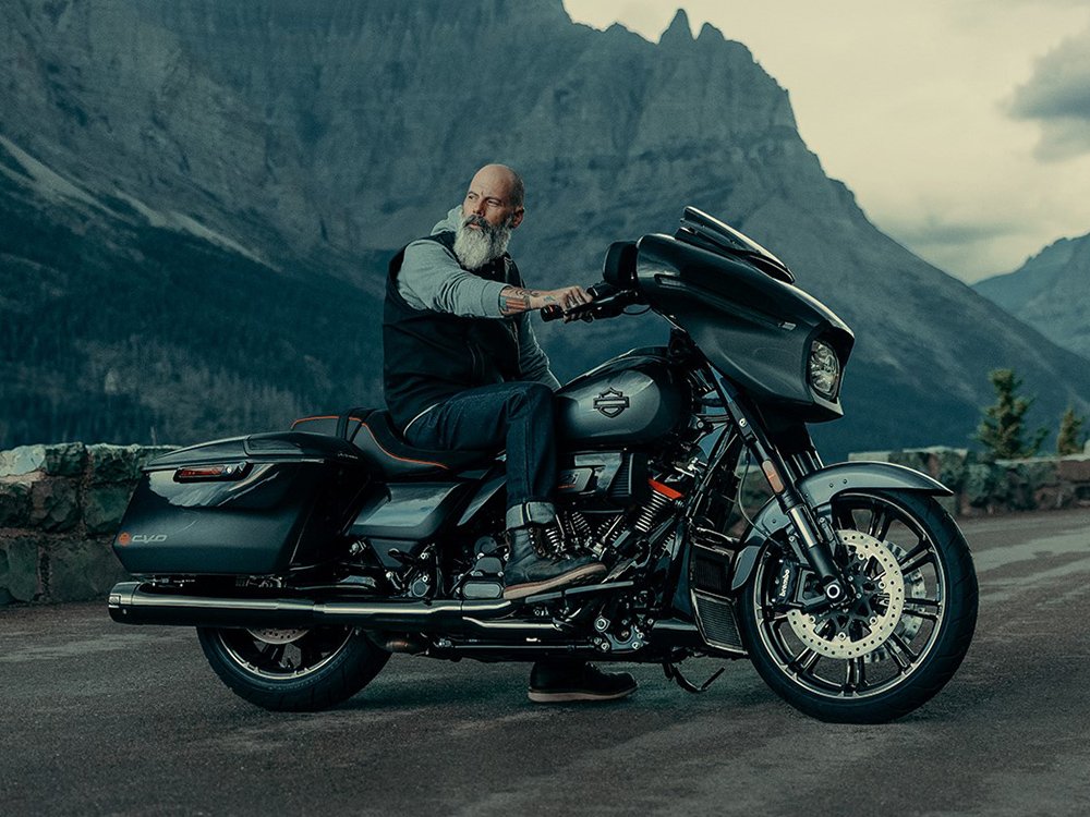 man on parked motorcycle with mountains in background